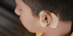Young boy wearing a hearing aid, showing NDIS assistive technology that supports hearing, communication and everyday independence.