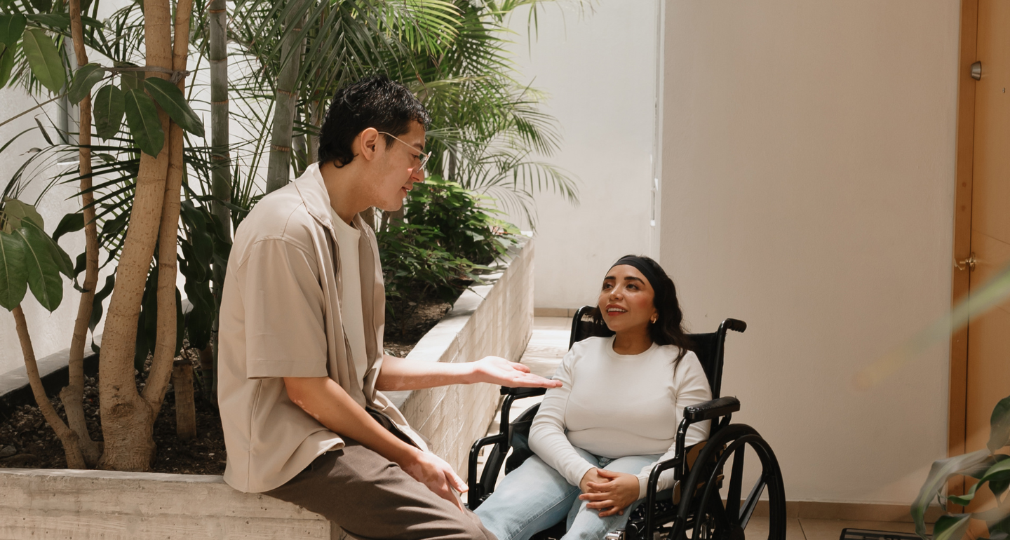 Disability Advocacy: Woman using a wheelchair engaged in a lively conversation with a man.