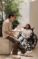 Disability Advocacy: Woman using a wheelchair engaged in a lively conversation with a man.