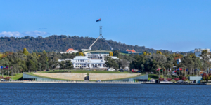 Australian Parliament House in Canberra viewed across Lake Burley Griffin, representing the passing of new NDIS integrity and safeguarding laws through Parliament in April 2026.