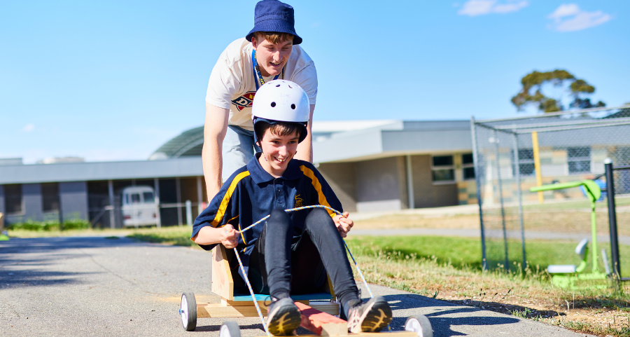 OSHC worker and student explore risk play with billy cart