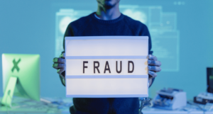 NDIS fraud: Man holding a sign with the word fraud written on it.