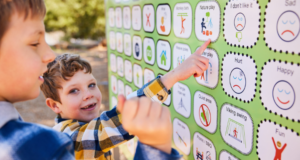 Two young boys interact with a communication board at an accessible playground, designed for children of all abilities.