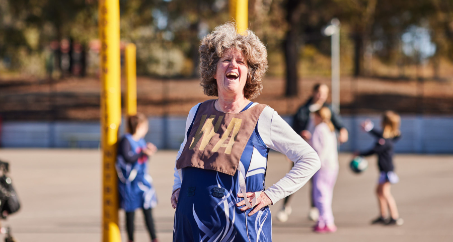 All Abilities Sport: Woman with a disability laughing while playing Wing Attack (WA) at an All Abilities netball game, enjoying the game on the court.