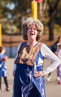 All Abilities Sport: Woman with a disability laughing while playing Wing Attack (WA) at an All Abilities netball game, enjoying the game on the court.