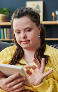 Refer to Lifely's NDIS & Disability Services: A young woman with Down syndrome smiles while filling out a referral form on her phone, showing independence and ease of access to disability and NDIS services.
